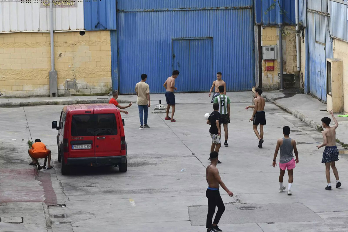 Varios menores extranjeros no acompañados juegan al fútbol en las naves del Tarajal (Ceuta). Europa Press